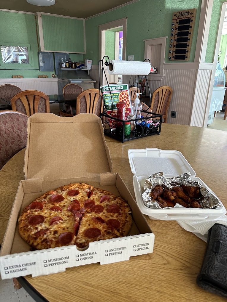 Fresh pepperoni pizza and saucy wings on a table in the Pizza Express dining room